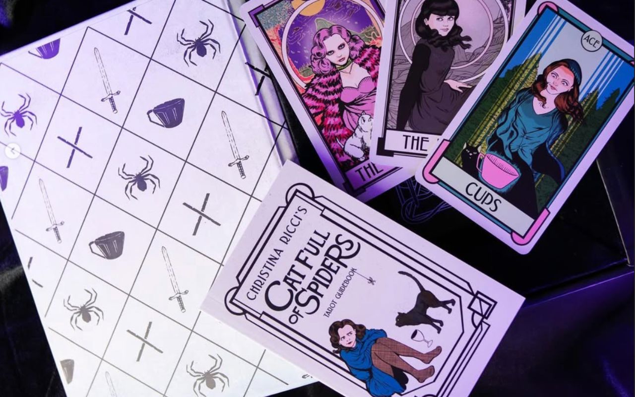Cat Full of Spiders tarot cards and guidebook laid out on a purple cloth